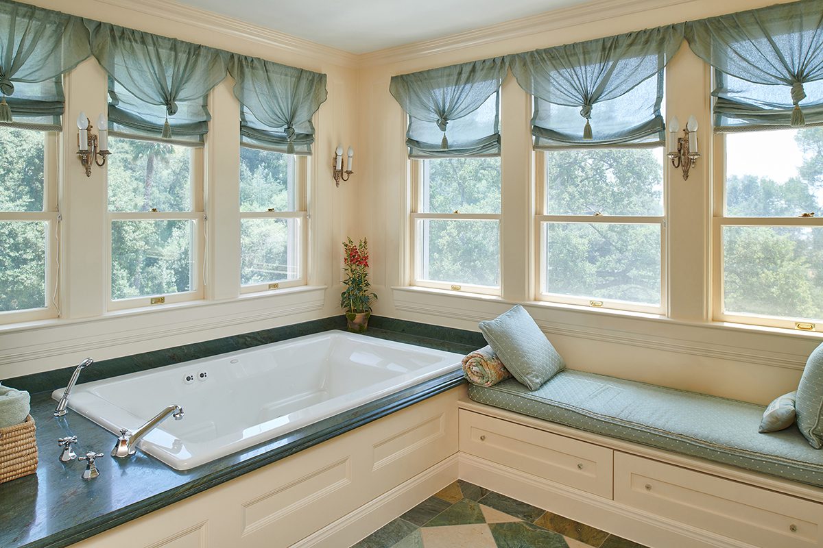 A large bathroom with a tub and window seat.
