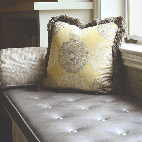 A pillow on top of a bed in front of a window.