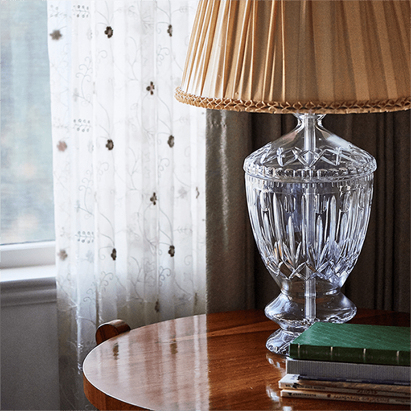 A lamp on top of a table next to books.